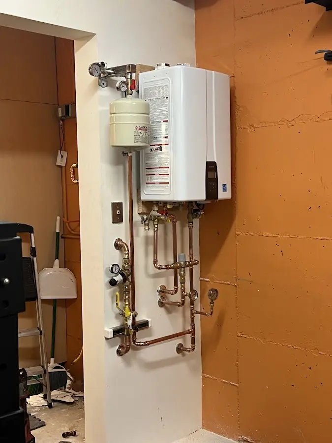 Plumbing technician inspecting water heater connections in Tallassee
